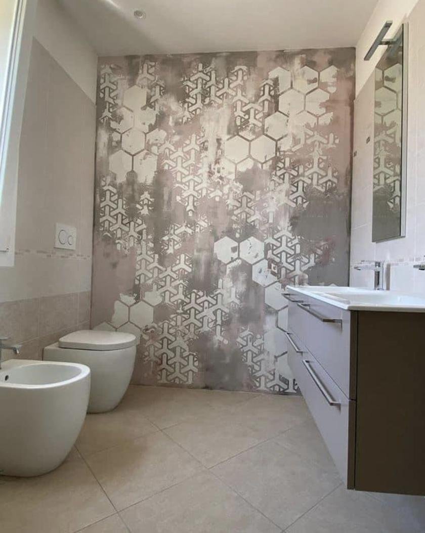 Pared de un baño con acabado decorativo de motivo geométrico de hexágonos en tonos rosa y gris