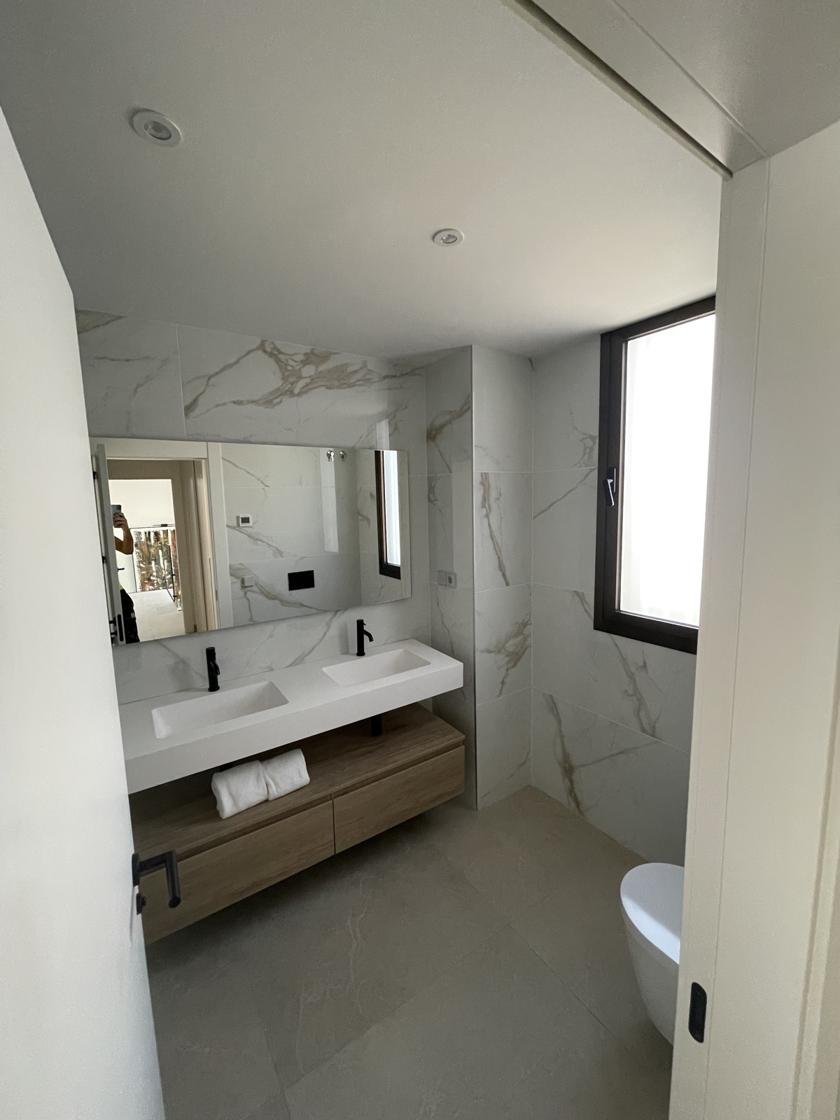 Baño terminado con azulejo efecto mármol, lavabo y claraboya