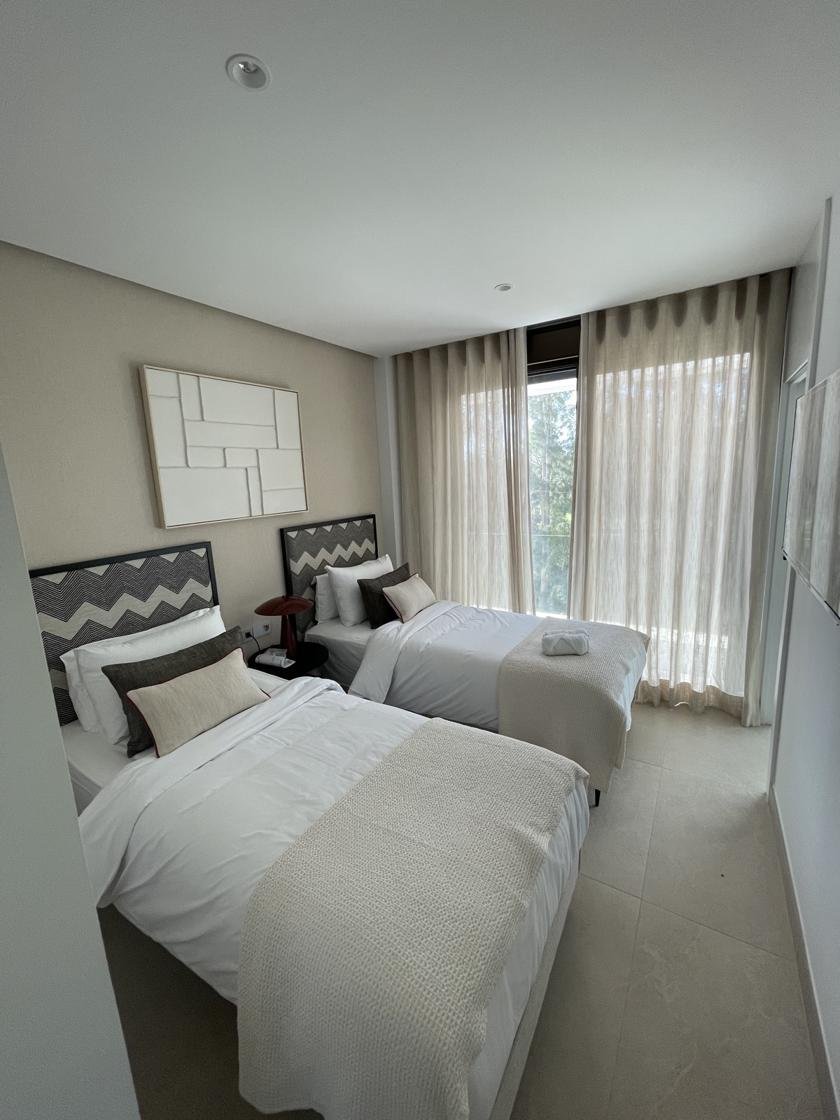 Dormitorio con dos camas individuales terminado, con cortinas largas