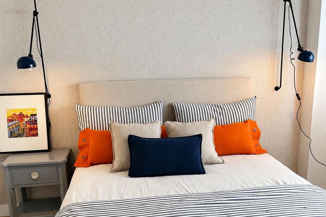 Dormitorio terminado con papel pintado de espiga, cabecero tapizado y lámparas de pared