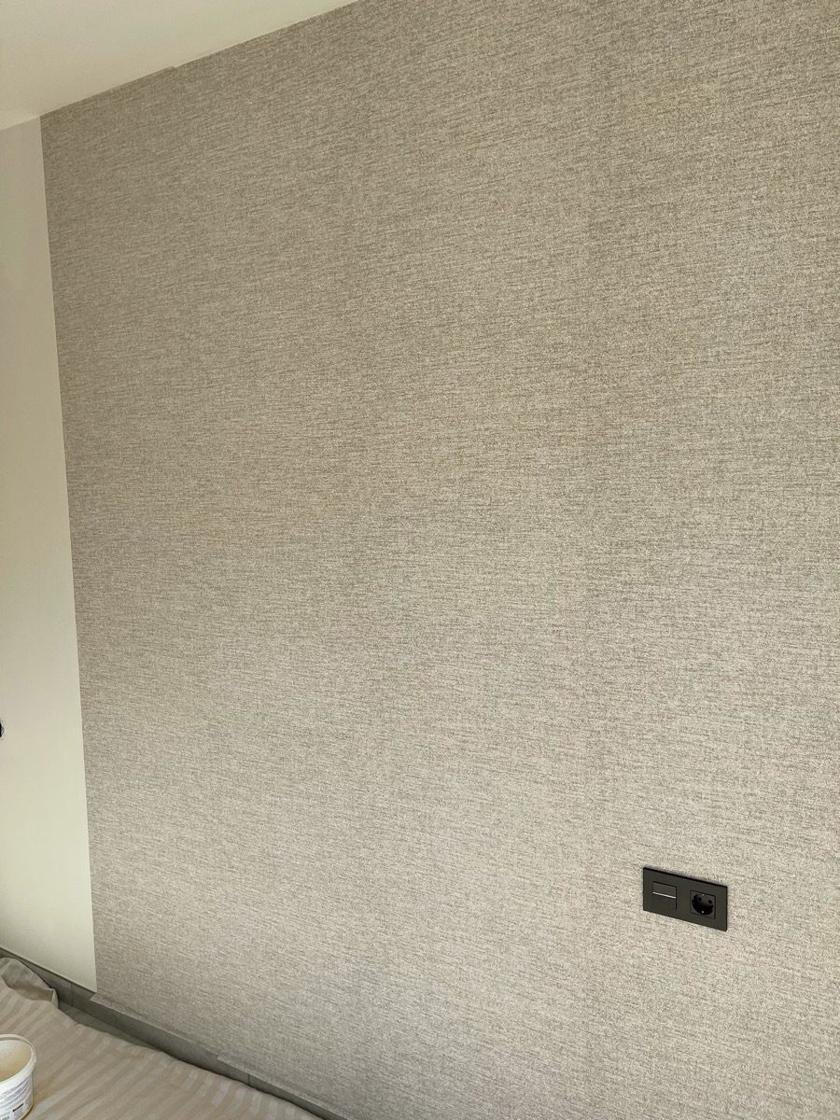 Pared de dormitorio con papel pintado de efecto tejido en tonos arena y gris