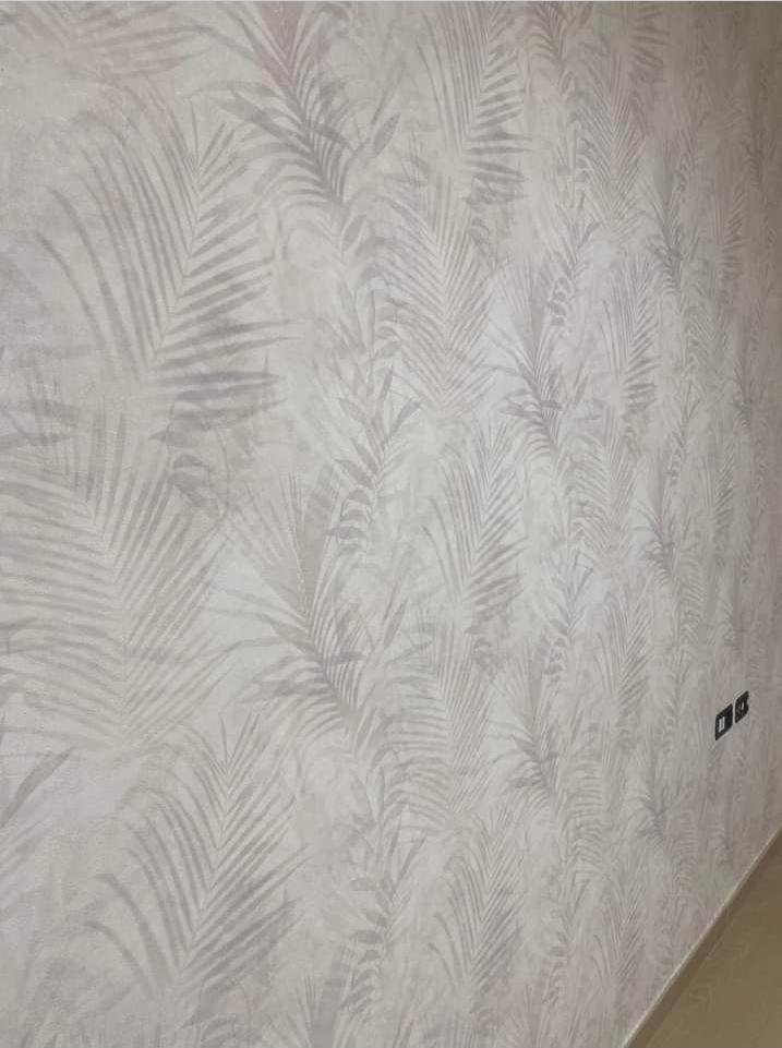 Pared con papel pintado de hojas de palma en tonos grises suaves