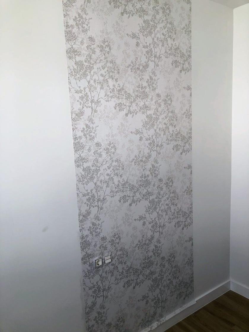 Franja de papel pintado de ramas en tonos grises colocada sobre una pared blanca