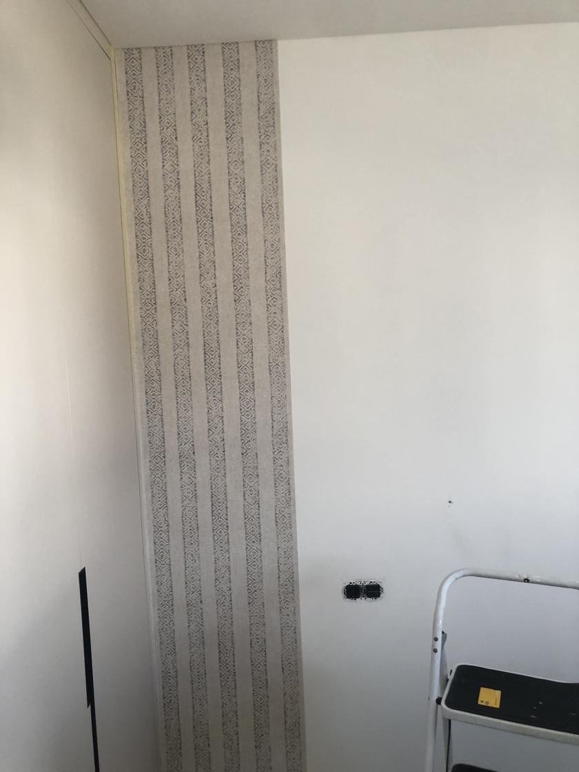 Pared con papel pintado de rayas verticales en gris y beige colocado en la parte baja