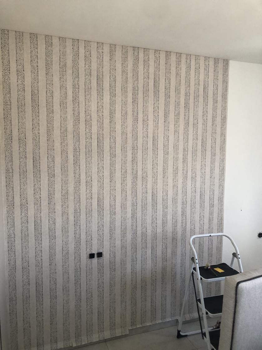 Pared completa con papel pintado de rayas verticales en gris y beige