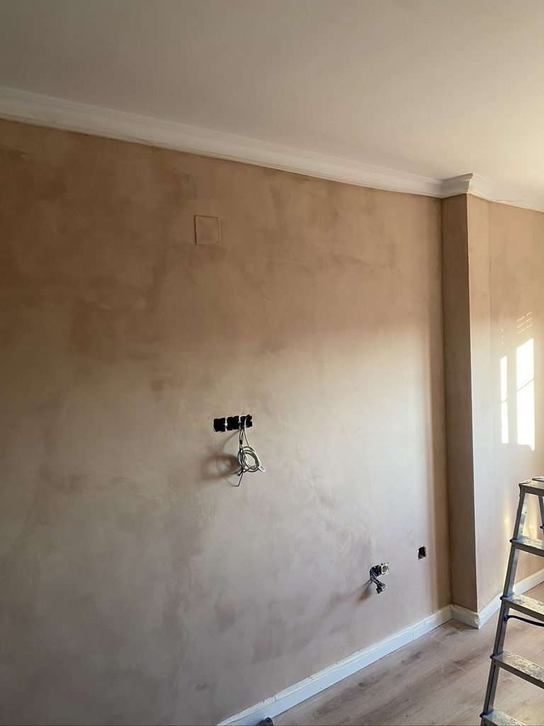 Pared de un salón acabada con estuco, de tono beige y aspecto veteado