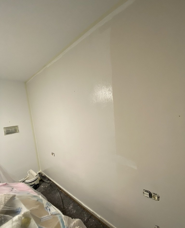 Pared de un piso en obra recién pintada, con el suelo protegido con plástico