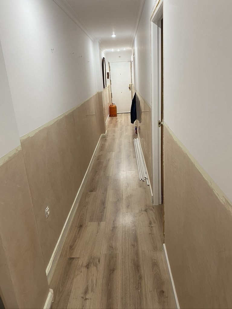 Pasillo de un piso en obra con panel de madera a media altura en las paredes