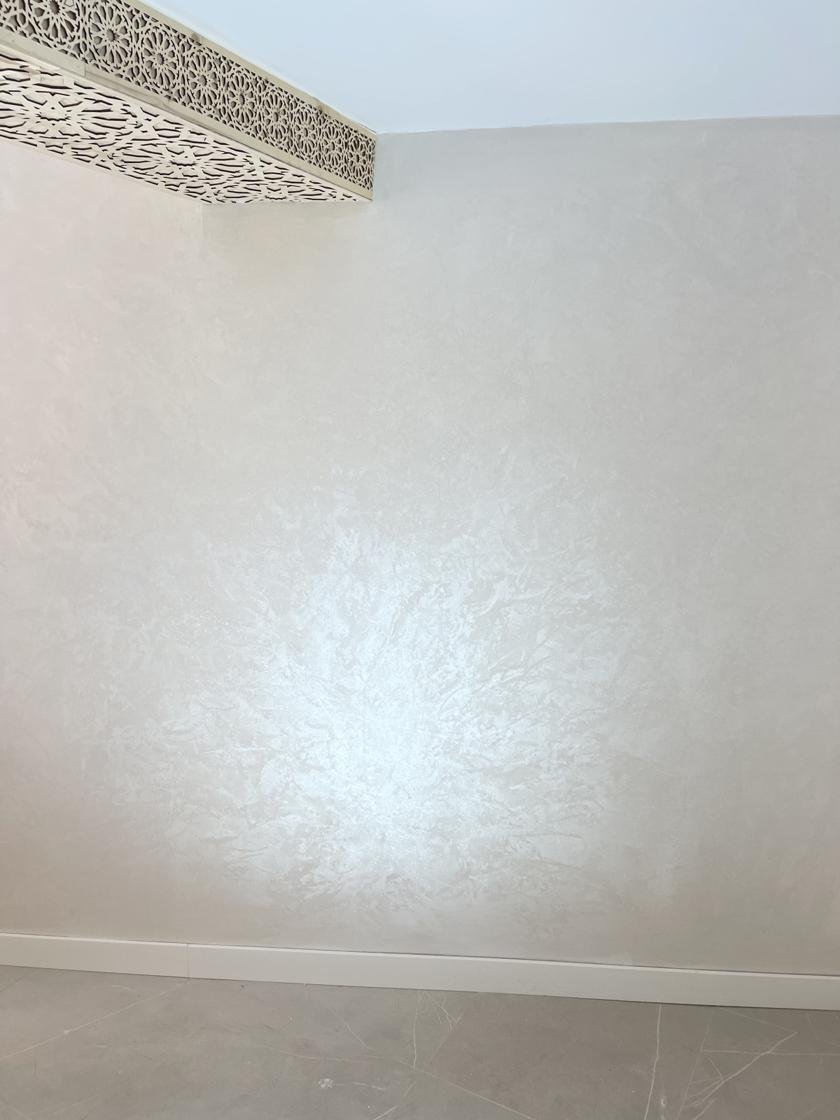Detalle de pared con pintura decorativa efecto damasco reflejando la luz