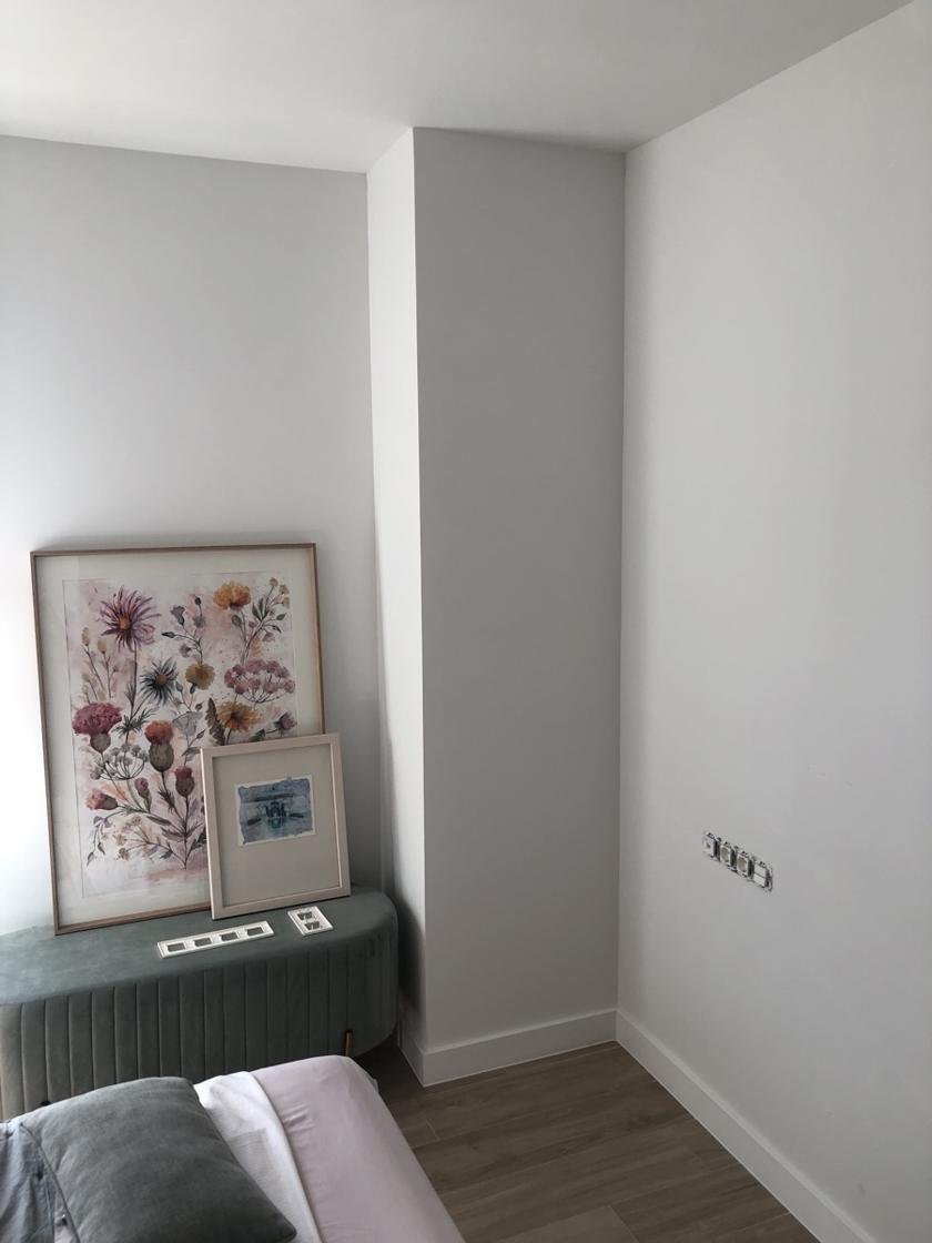 Dormitorio con paredes pintadas en gris muy claro y rodapié blanco