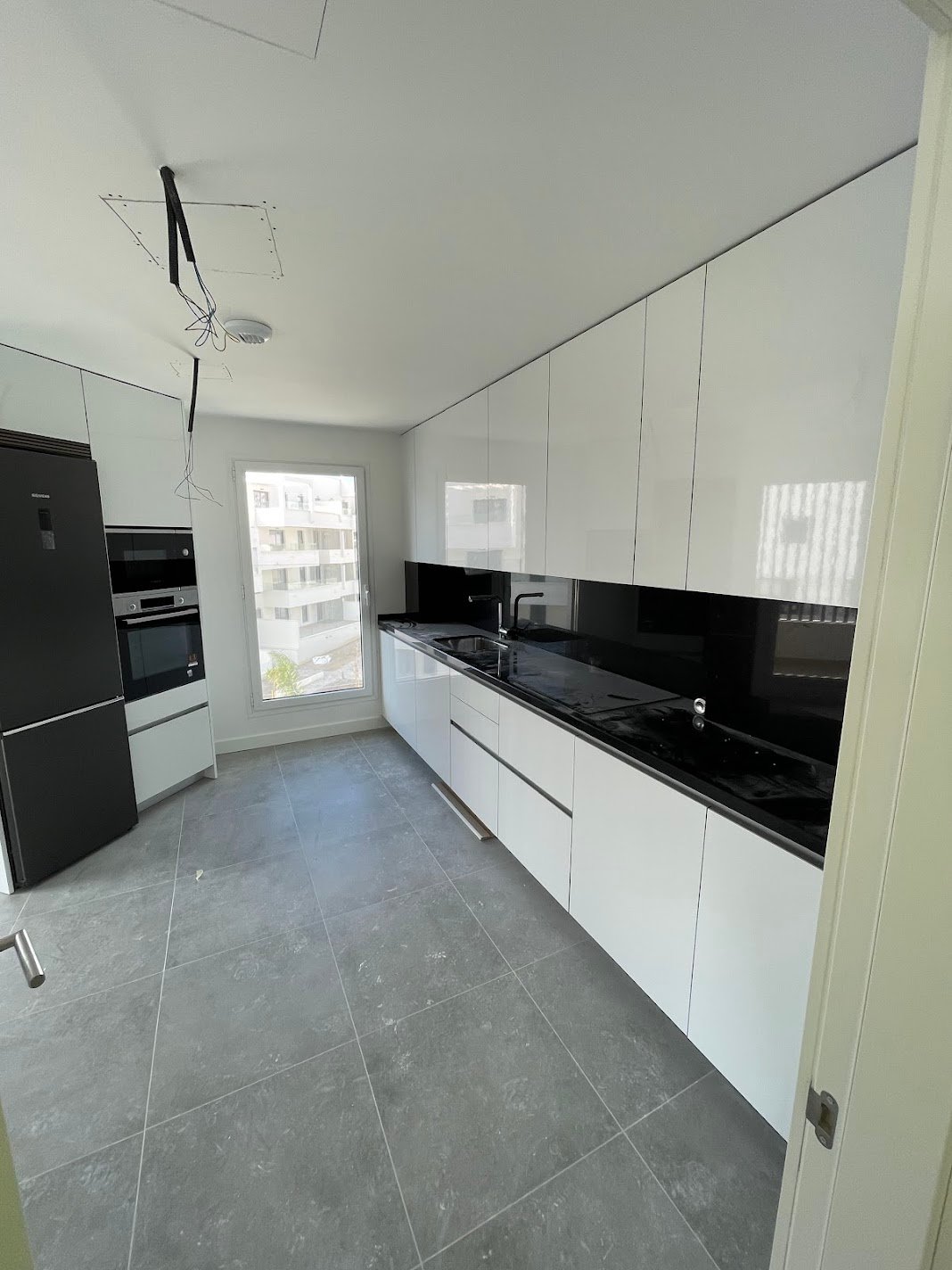 Reforma de cocina moderna blanca con encimera negra en Marbella - PintaReformas